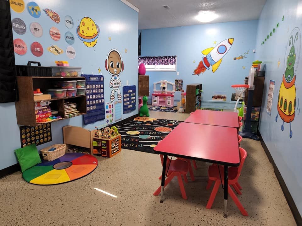 Children's classroom with red tables and space-themed wall decorations