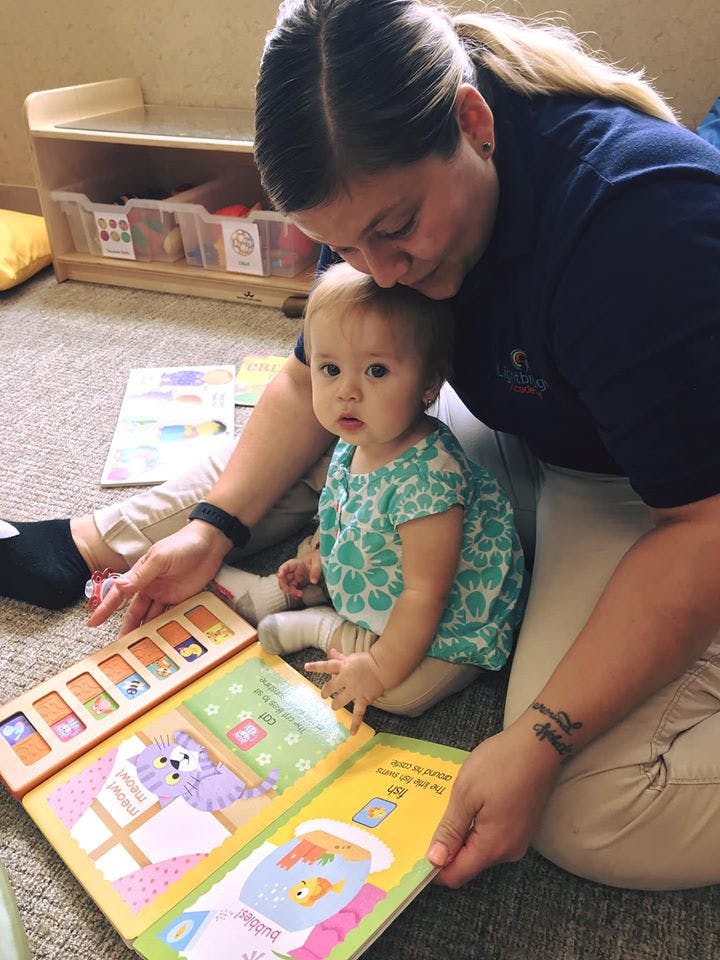 Person and child sitting on floor reading a book