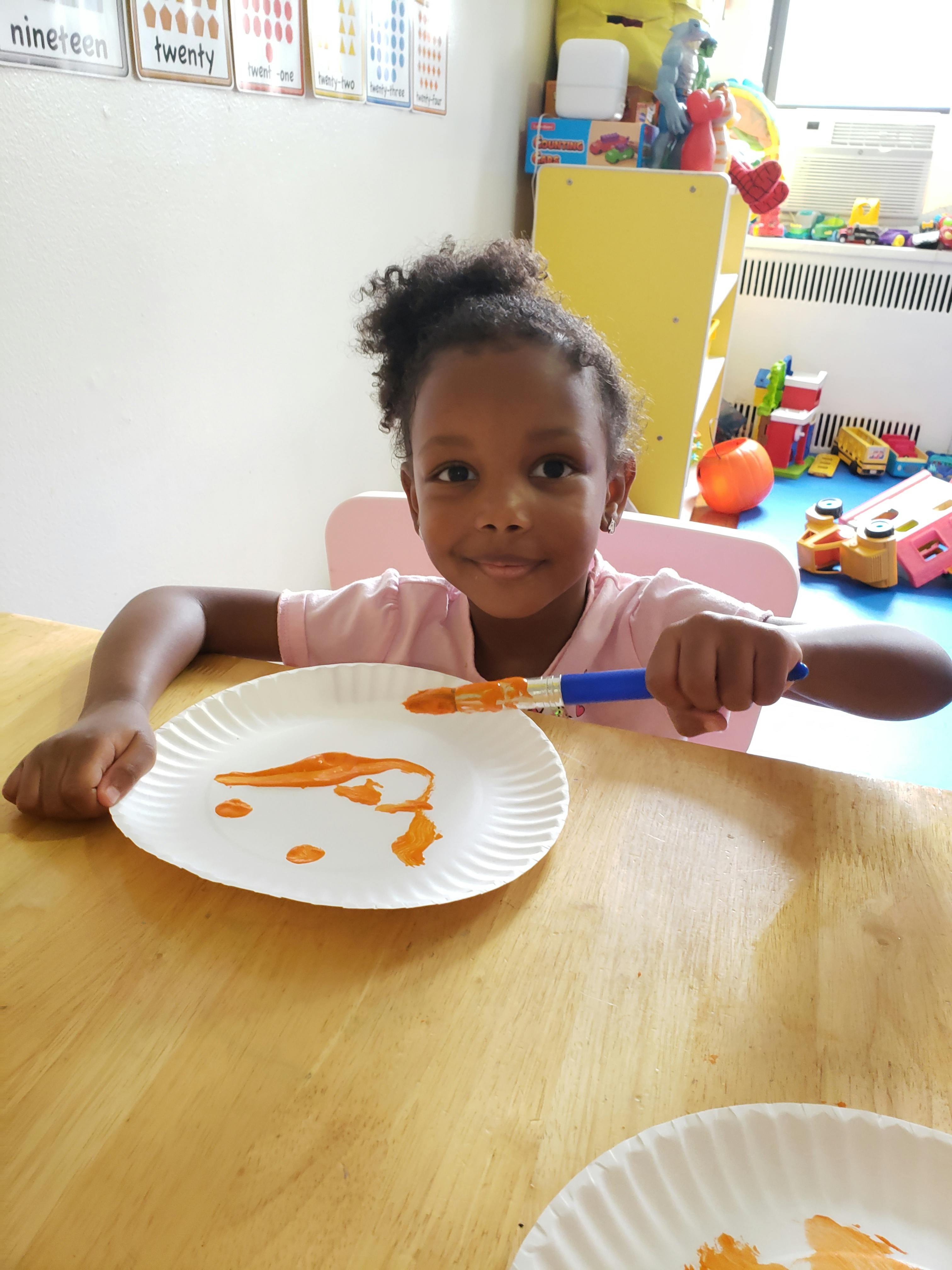 Child painting on a paper plate