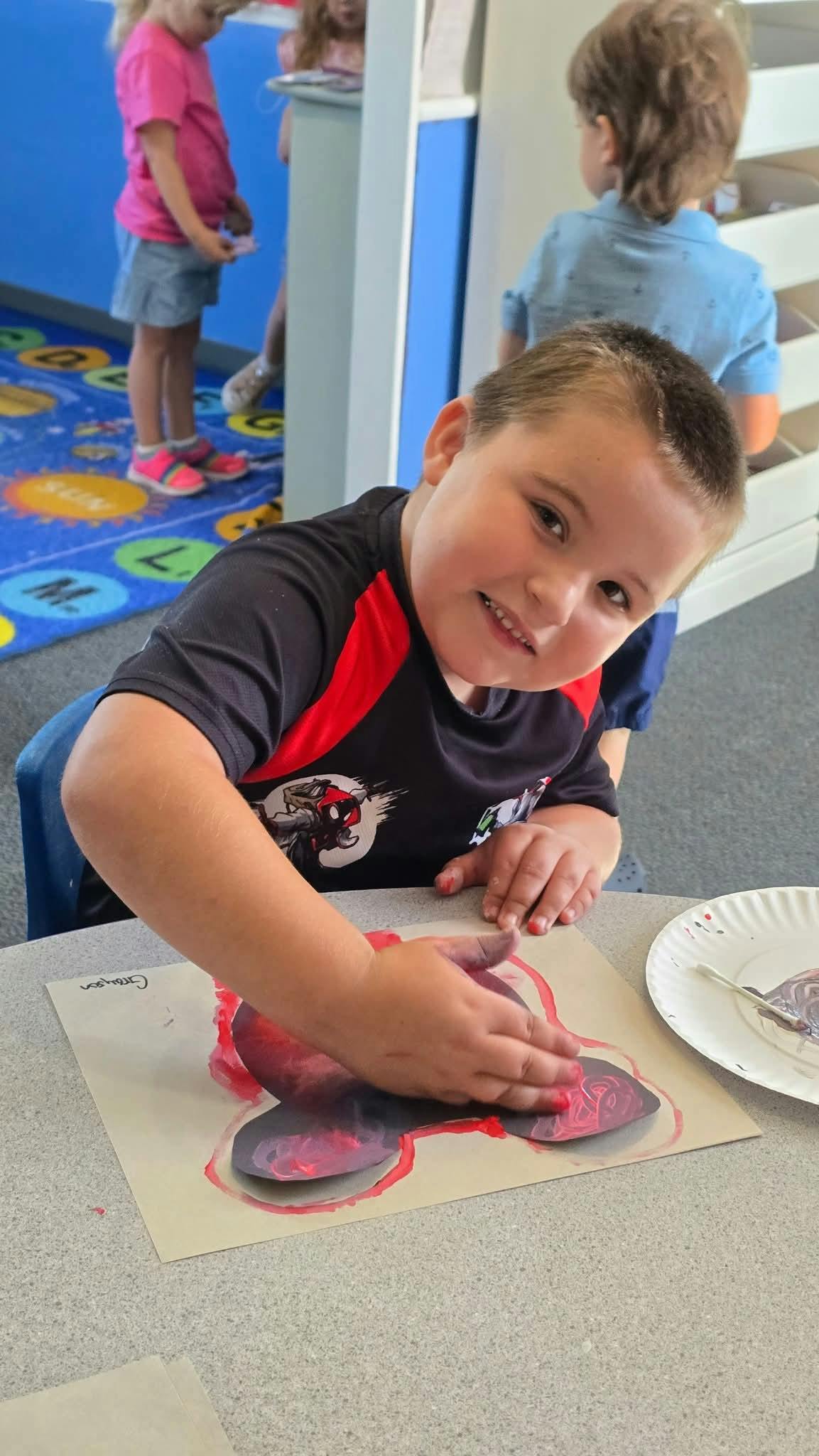 Child painting a butterfly shape on paper