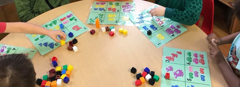 Children playing a board game with colorful pieces at a table