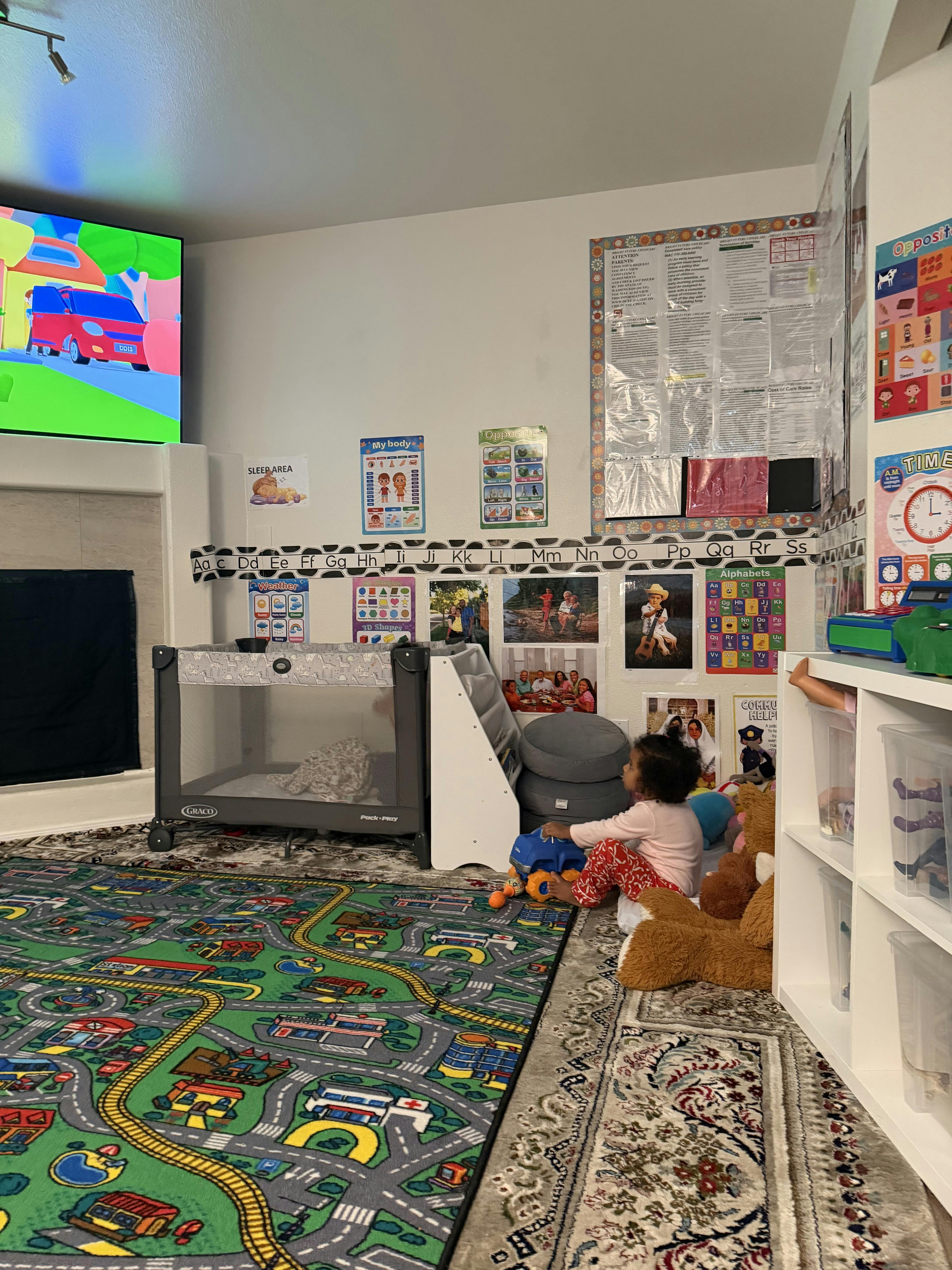 Child playing with a toy truck in a childcare room with educational posters