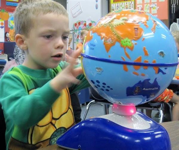 Child touching a globe in a classroom