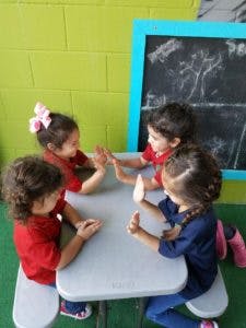 Four children playing a hand game at a table