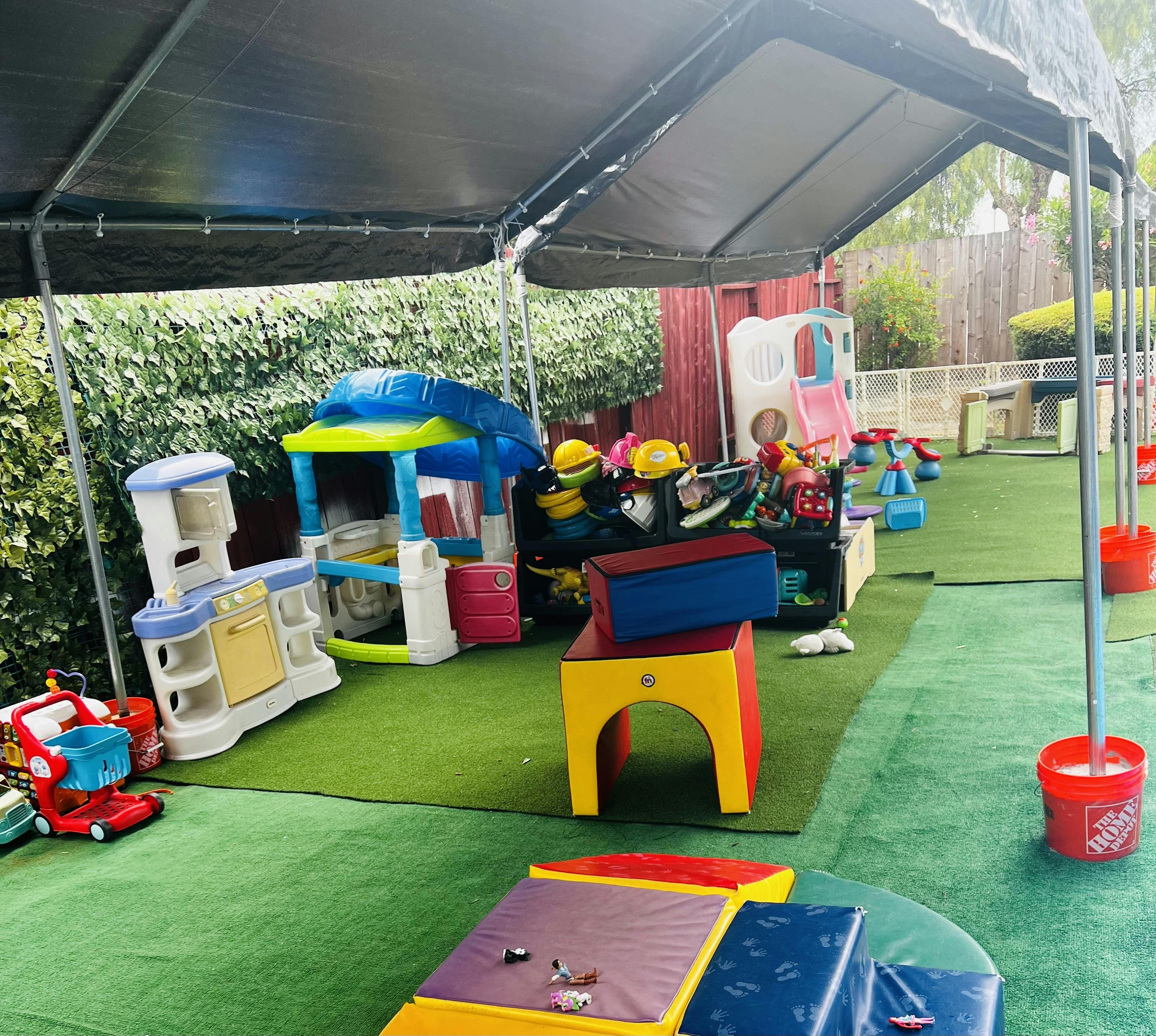 Children's playground with a tent covering playhouses, slides, and toys