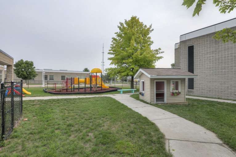 Playground with a small playhouse and a sidewalk