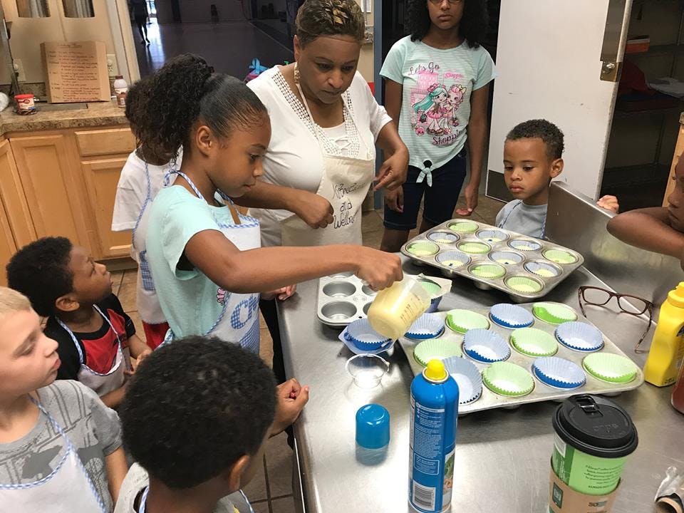 Person and children baking cupcakes in a kitchen