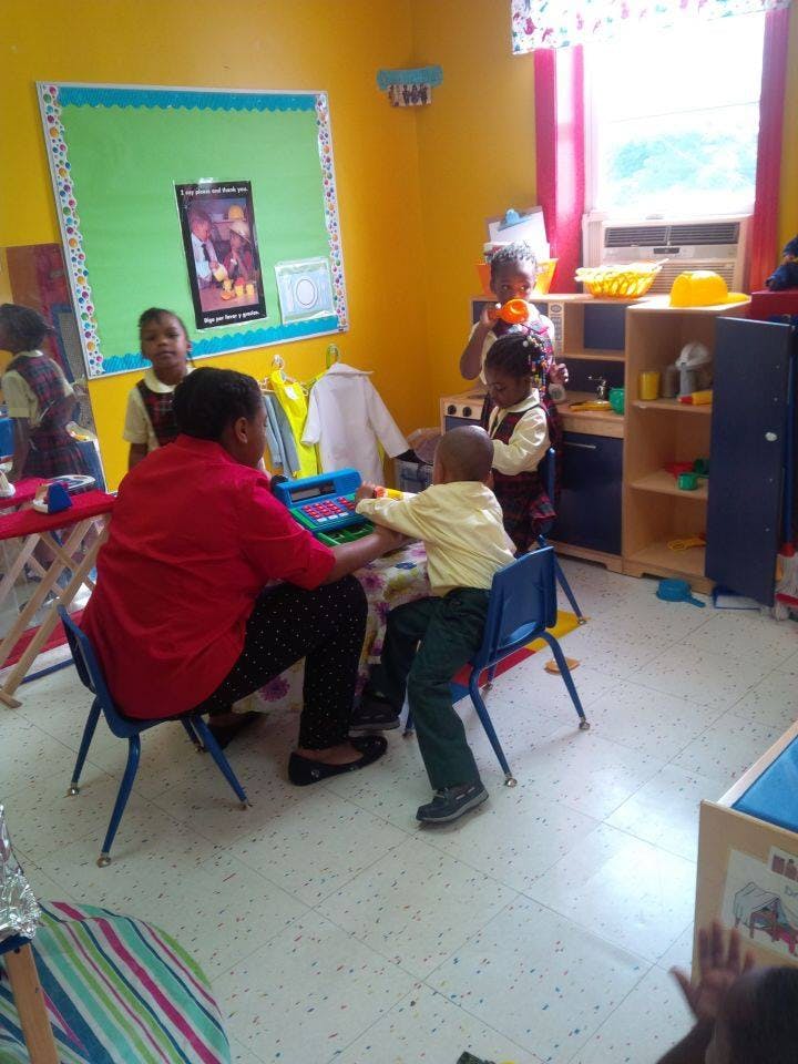 Adult and child playing with a toy in a classroom