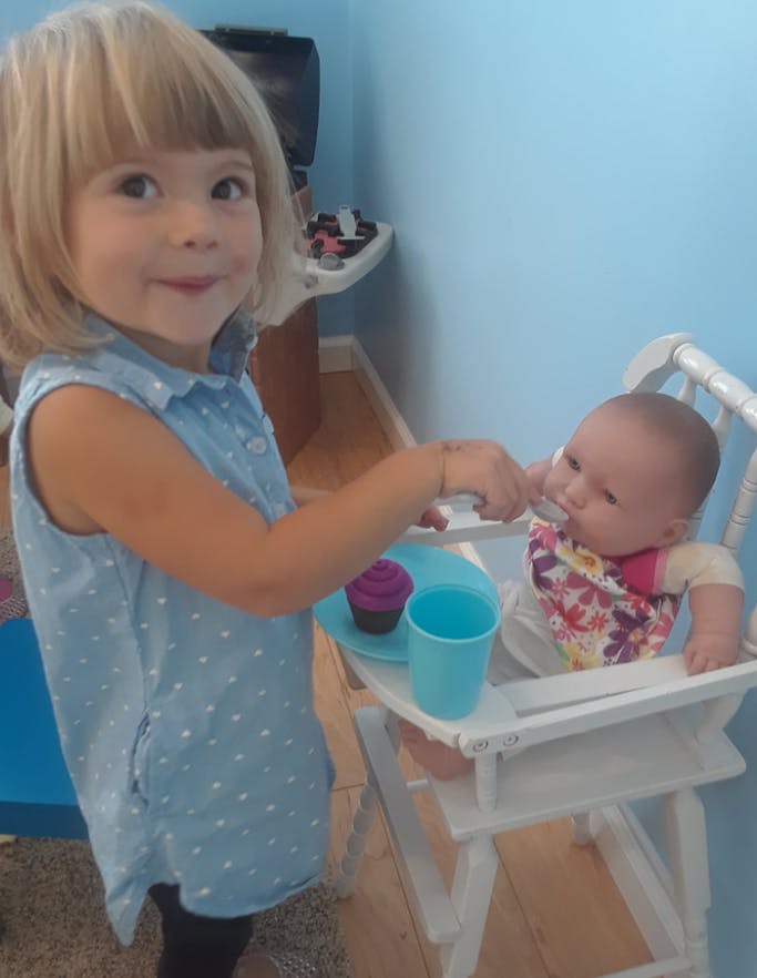 Child feeding a doll in a high chair