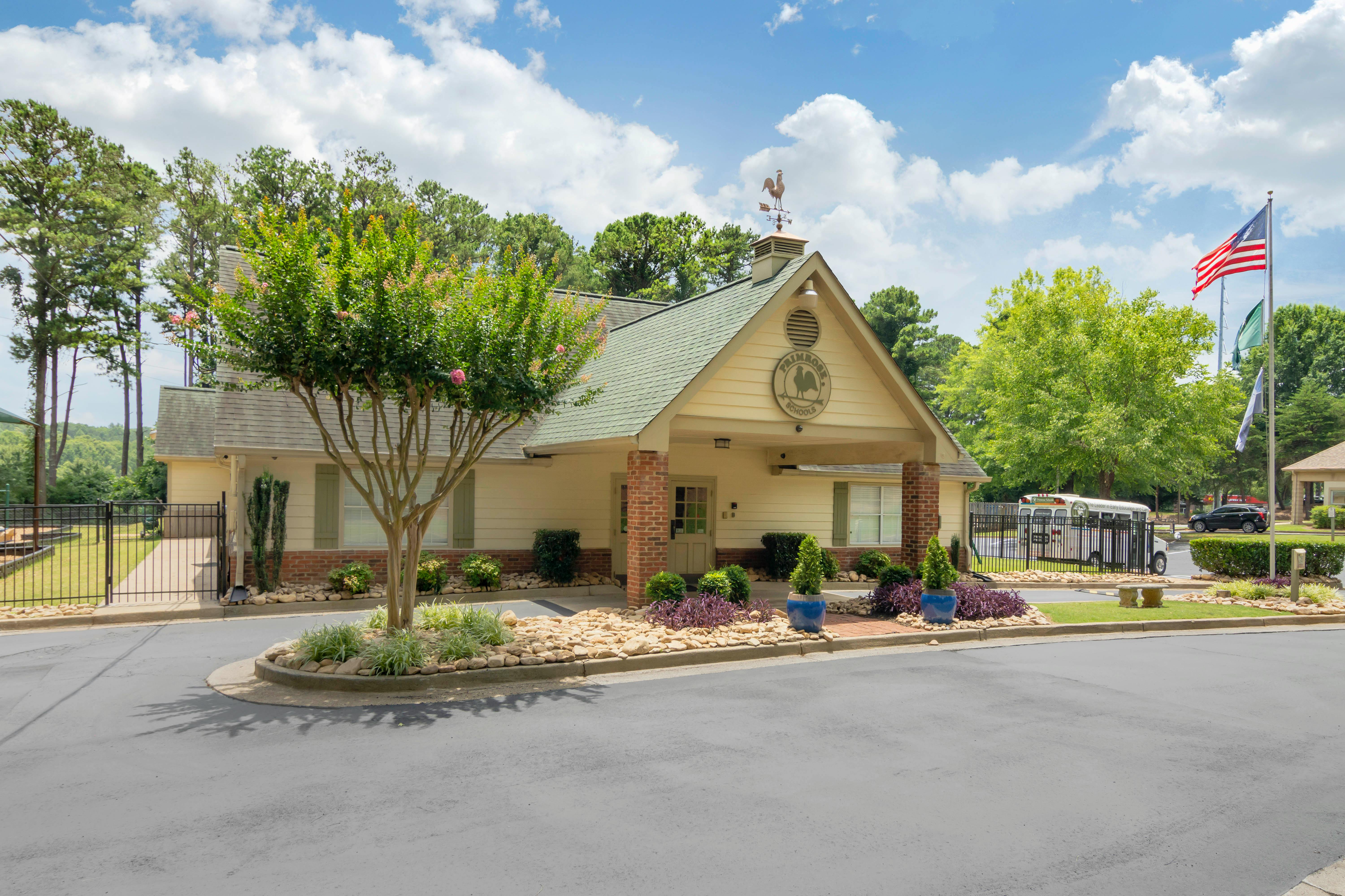yellow building with green roof and front porch, weathervane on peak