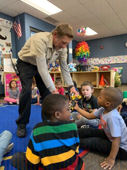 Adult showing a toy to children in a classroom