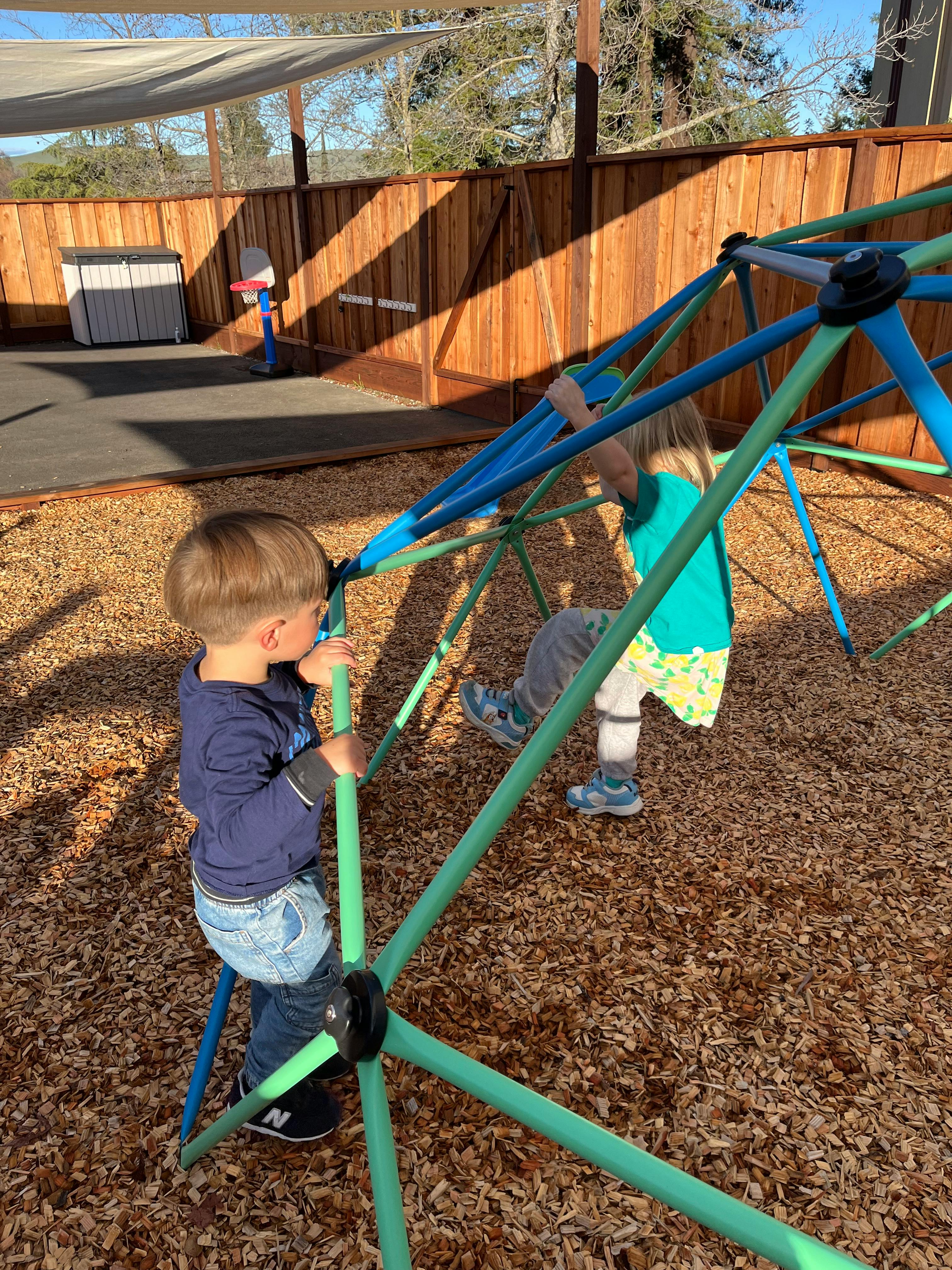 Two children climbing on a jungle gym