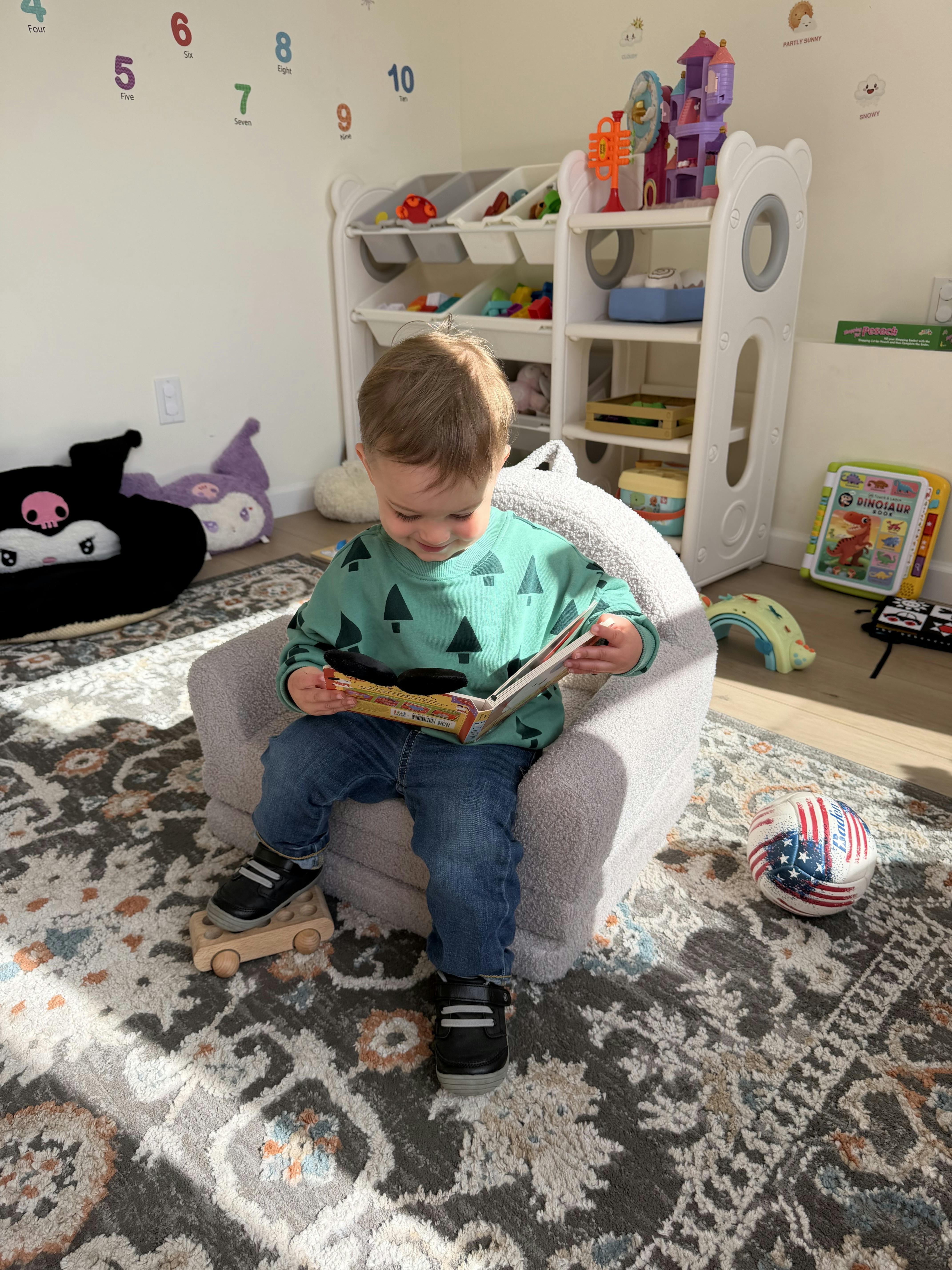 Child sitting in a beanbag chair reading a book in a playroom