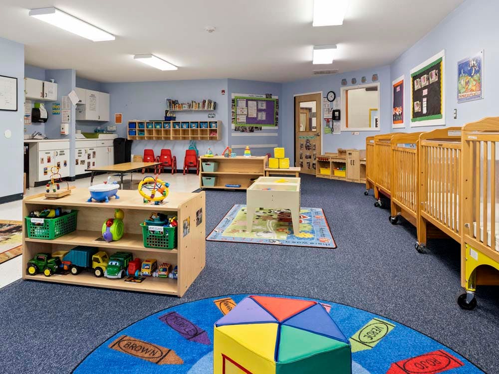 A colorful and spacious nursery room with cribs, play mats, and toys
