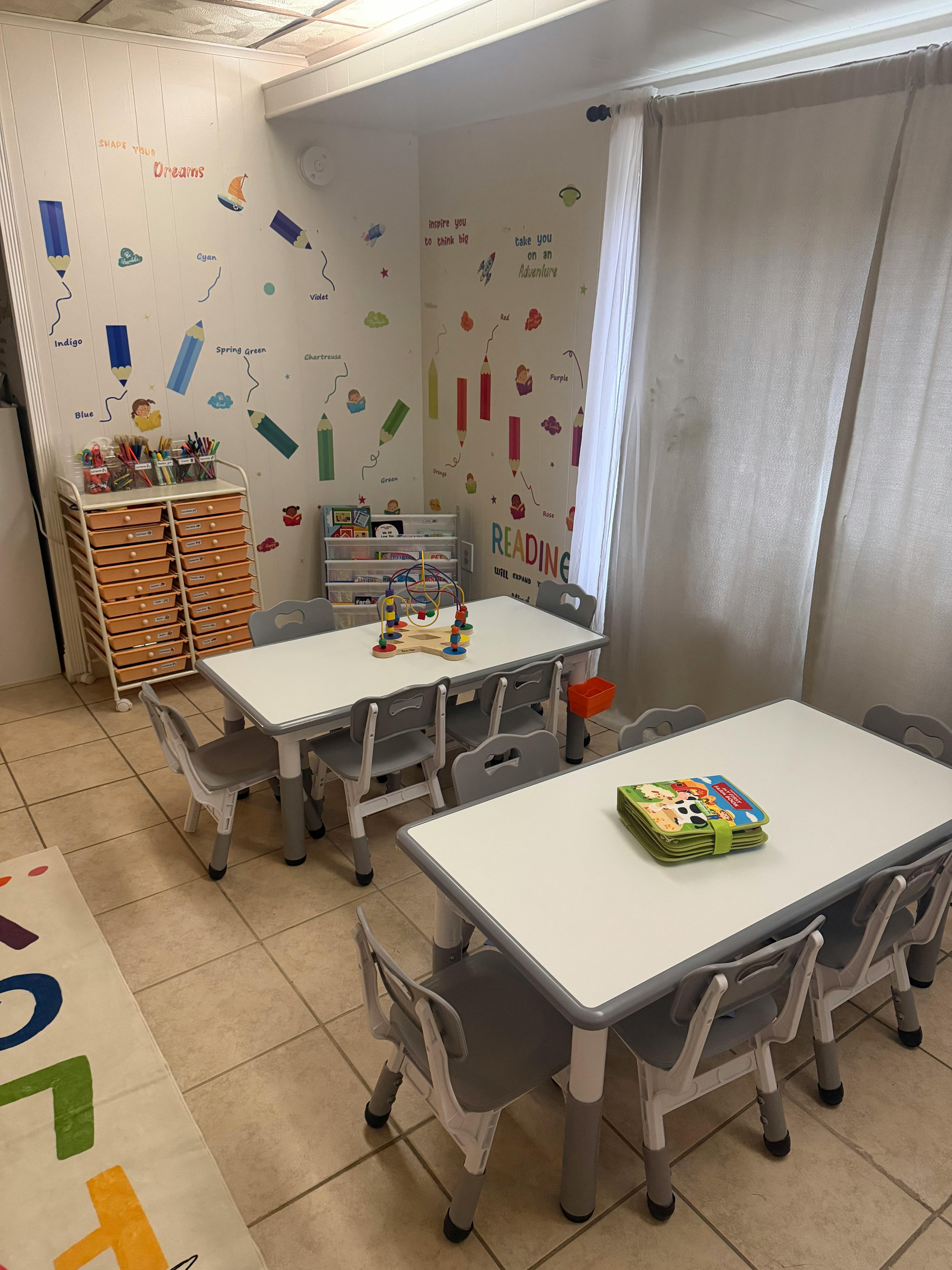 Children's classroom with two tables, chairs, wall decals, and storage cubbies