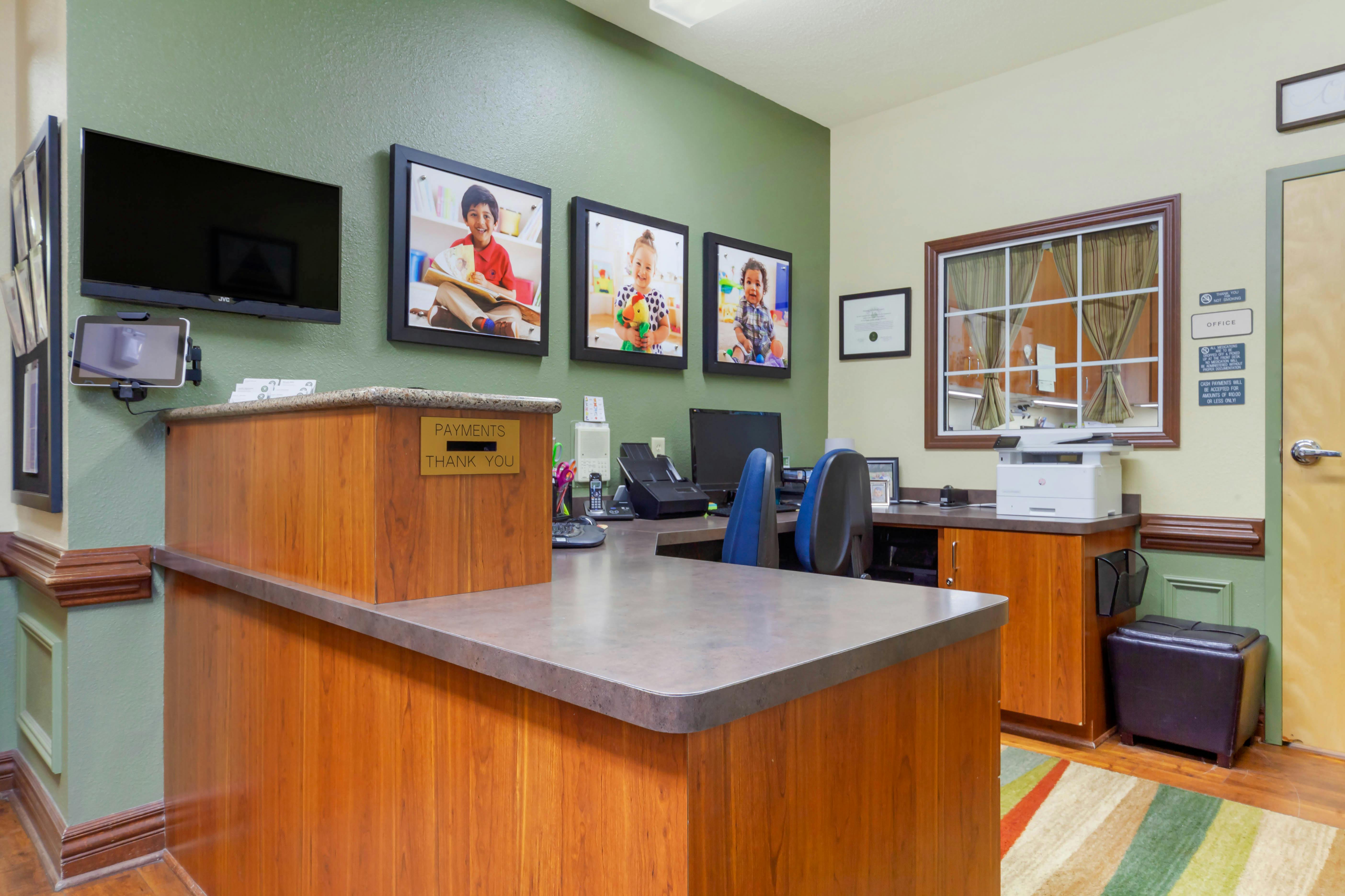 Reception desk with three framed photos of children above it