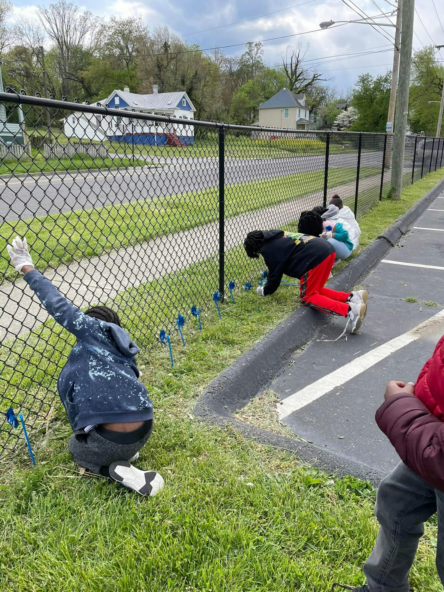 People kneeling by a fence, placing small blue flags in the grass