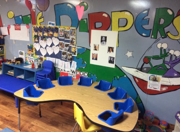 Classroom with a curved table and blue chairs, colorful wall murals