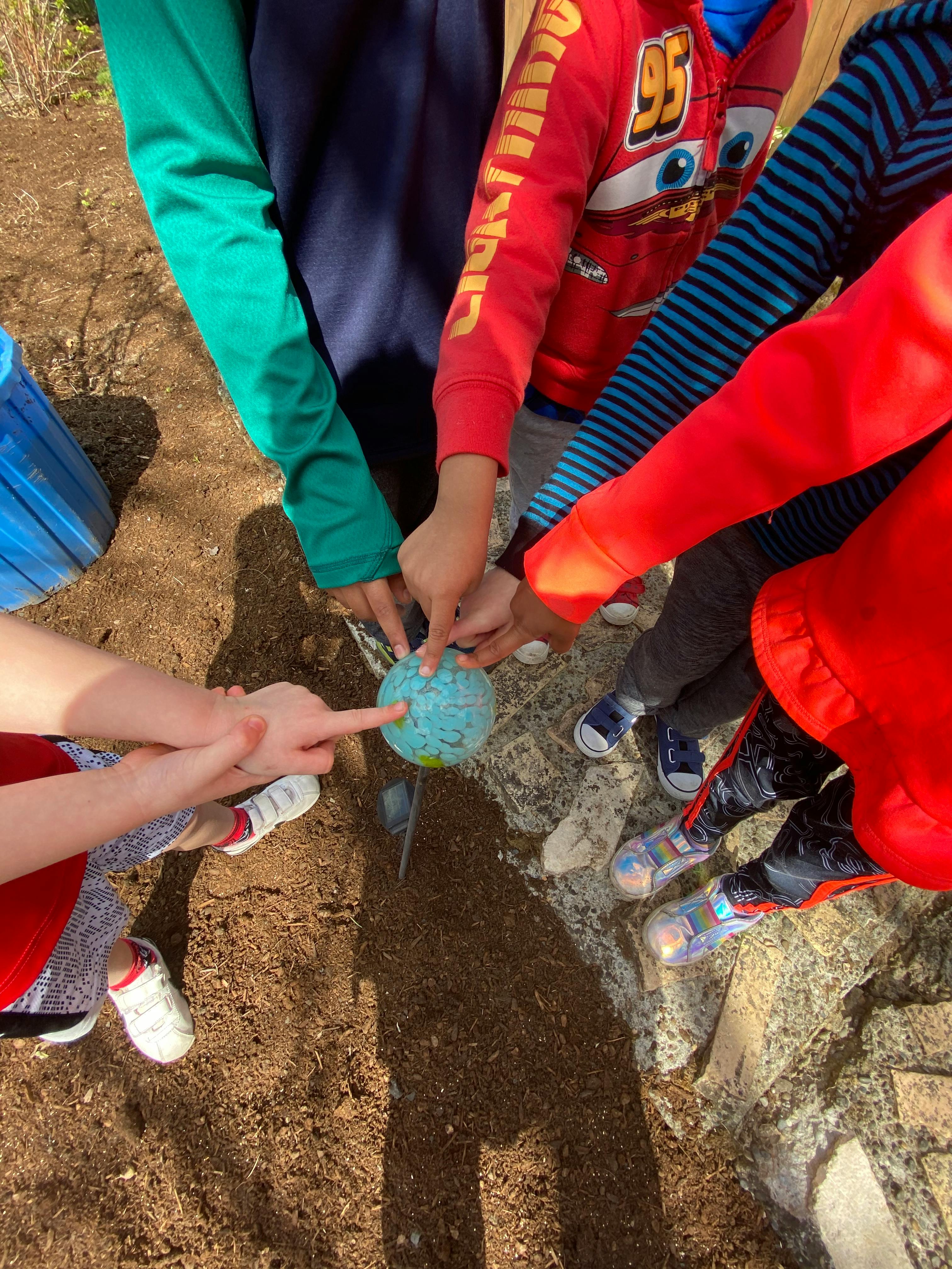 Children's hands touching a small globe