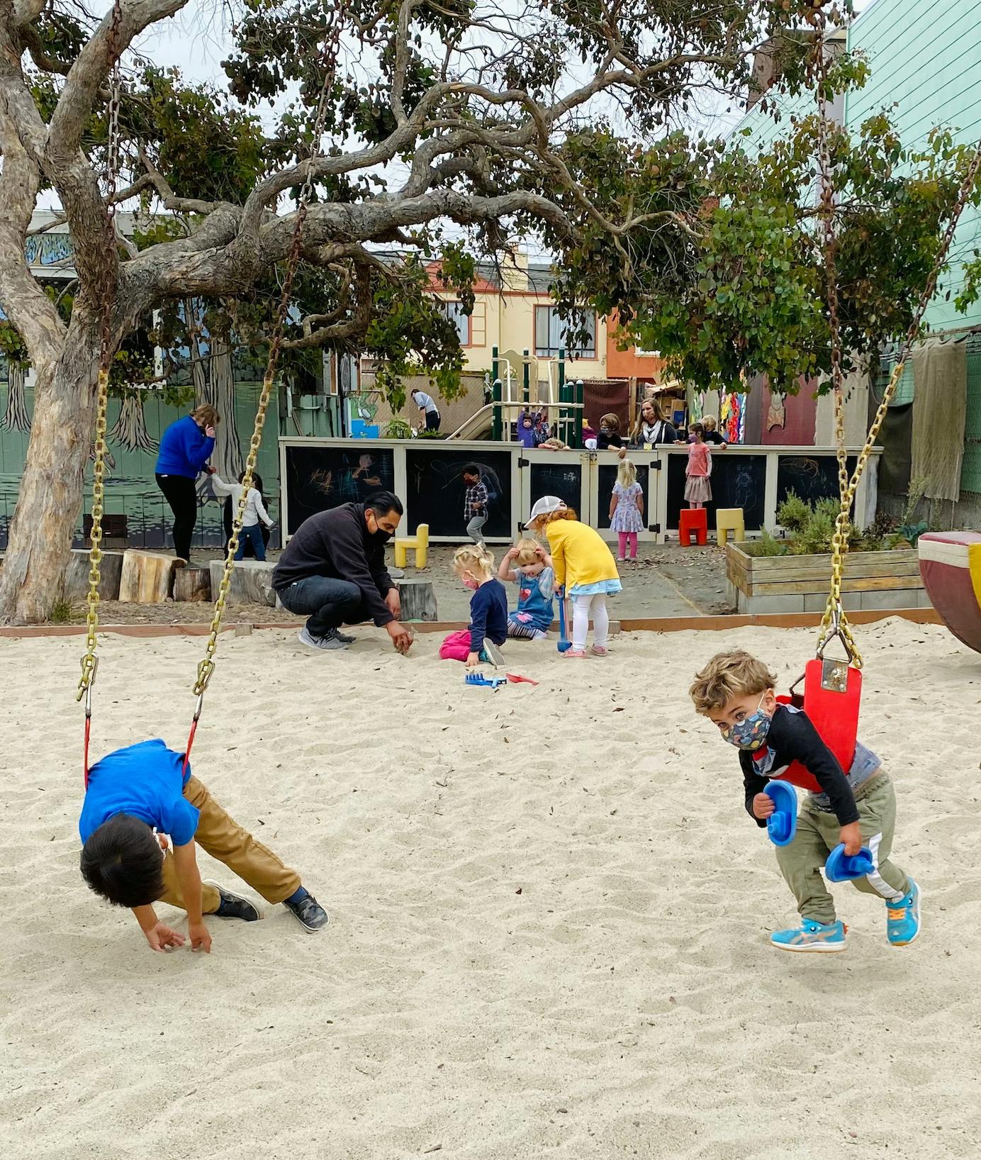 Children and adults playing in a sandy playground