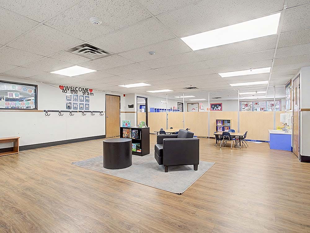 Classroom with tables, chairs, and play areas divided by partitions