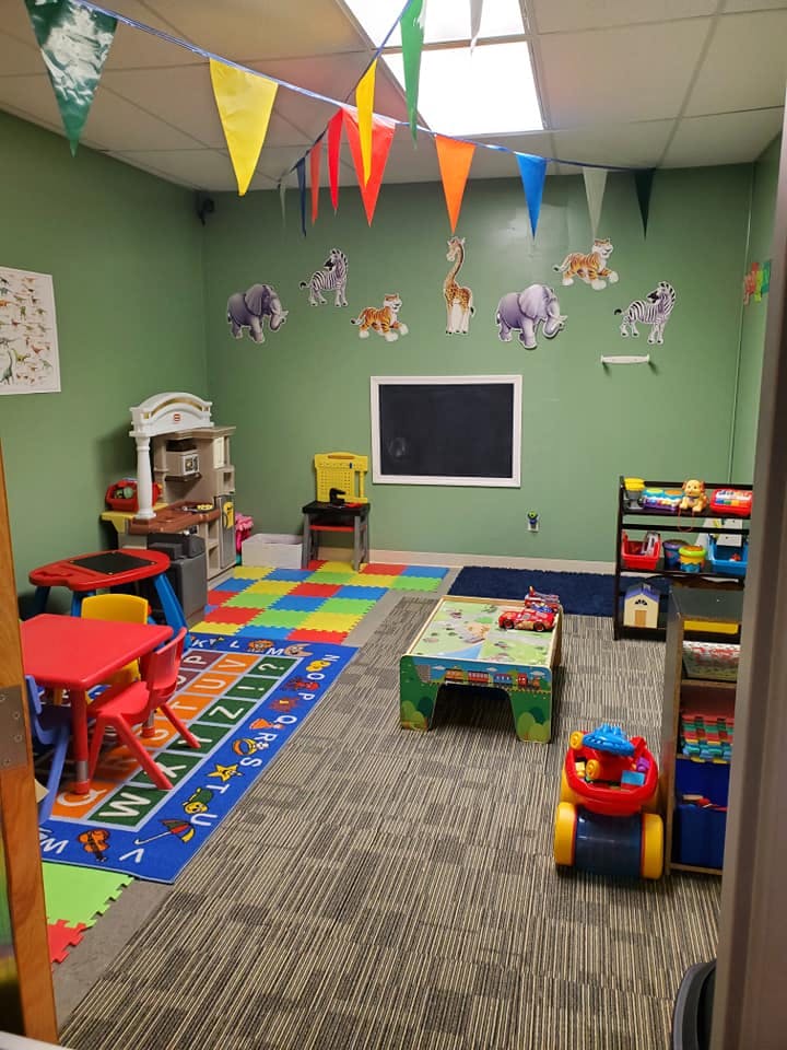 Playroom with colorful rugs, small tables, and toys