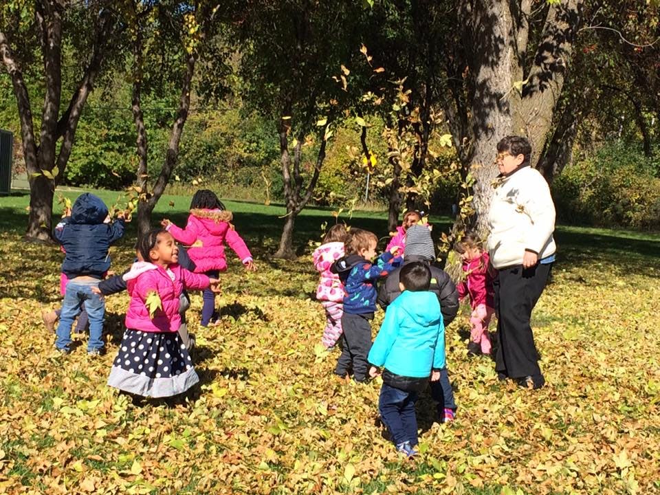 Adult and children playing in fallen leaves outdoors