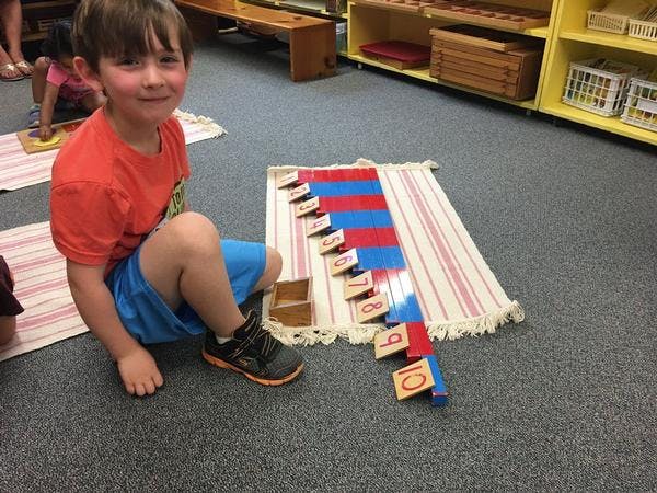 Child sitting on floor next to counting rods and number blocks