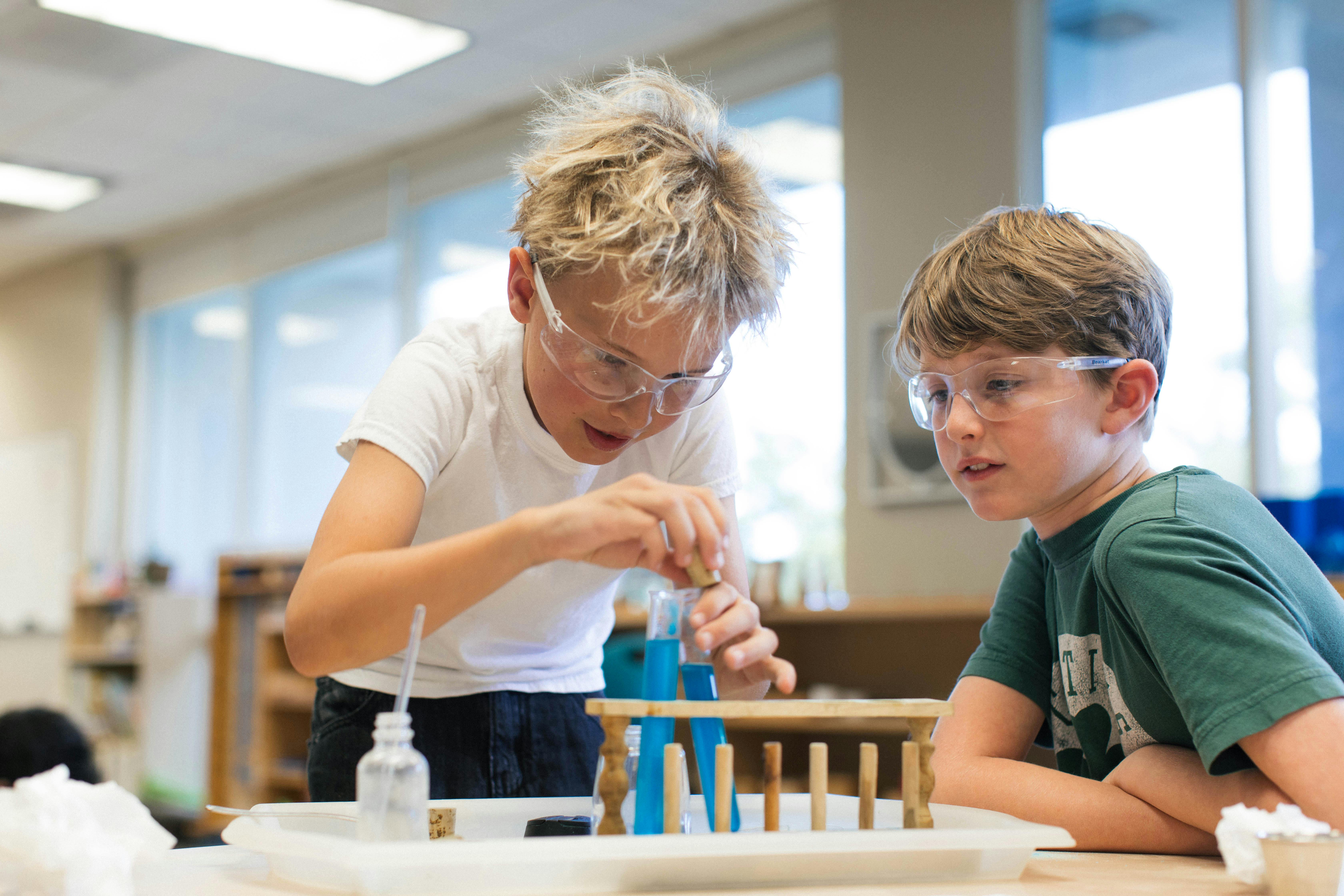 Two children in safety glasses doing a science experiment in a classroom