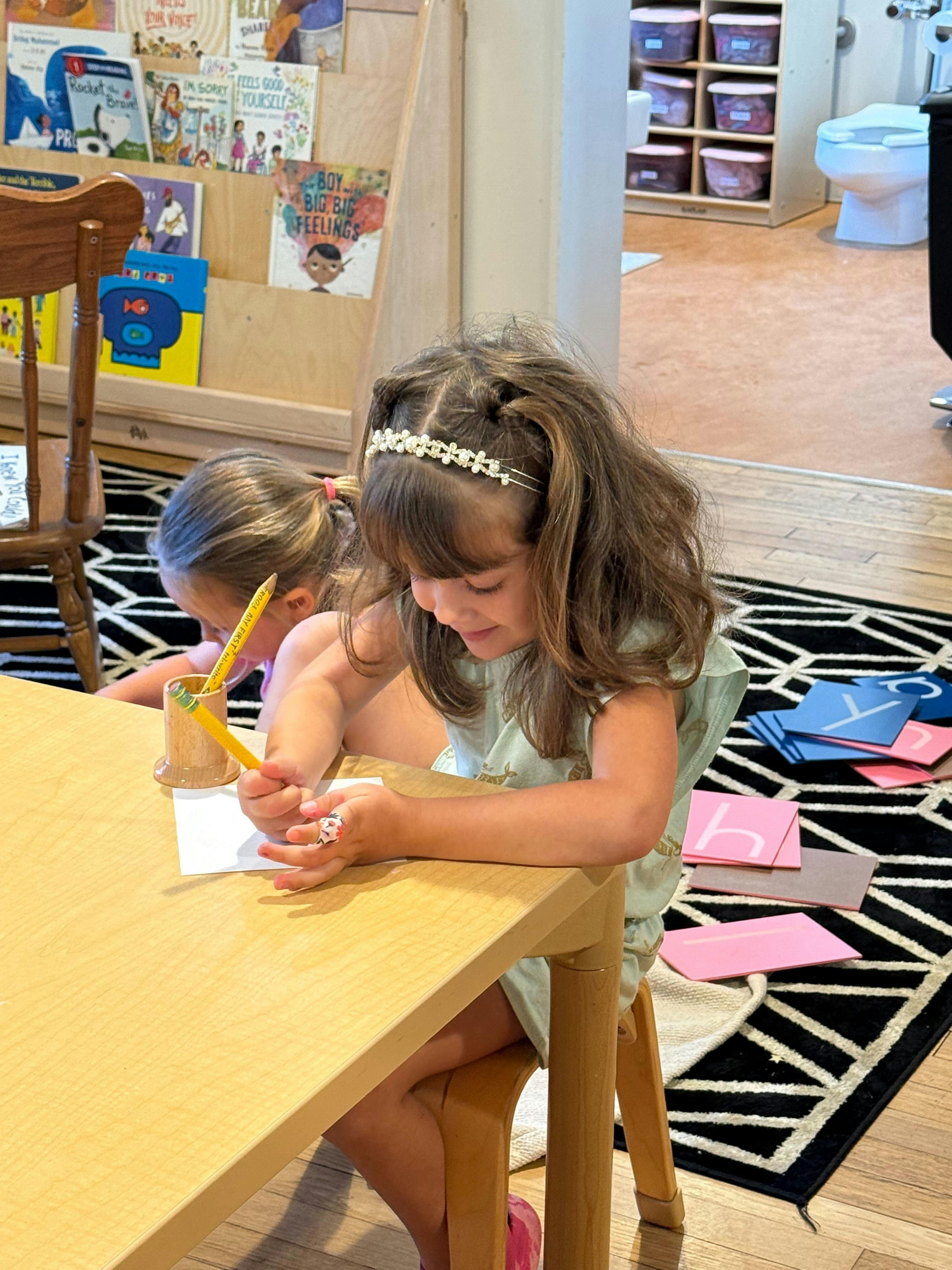 Two children drawing at a table in a classroom