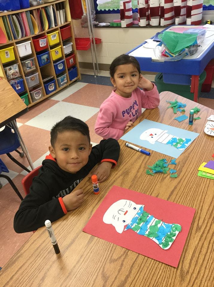 Two children sitting at a table with craft projects
