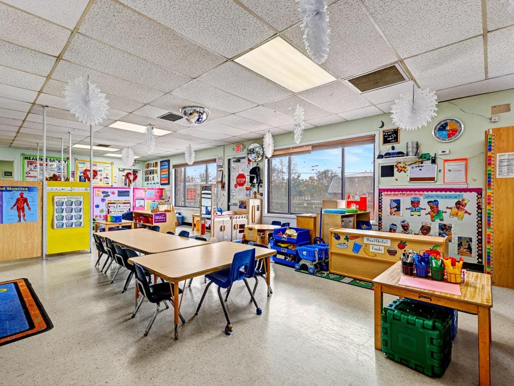 Empty classroom with tables, chairs, and learning materials