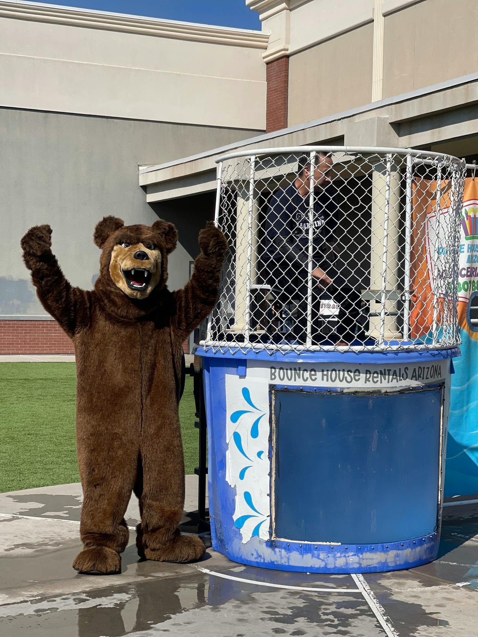Person in bear costume next to a dunk tank with a person inside