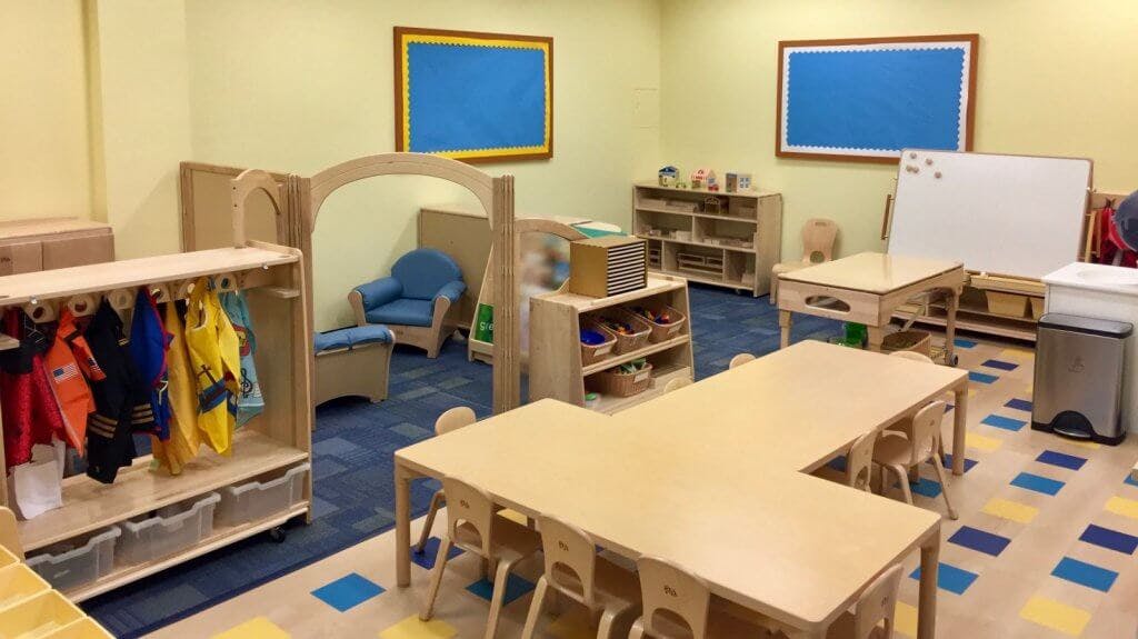 Empty classroom with small tables, chairs, and storage units