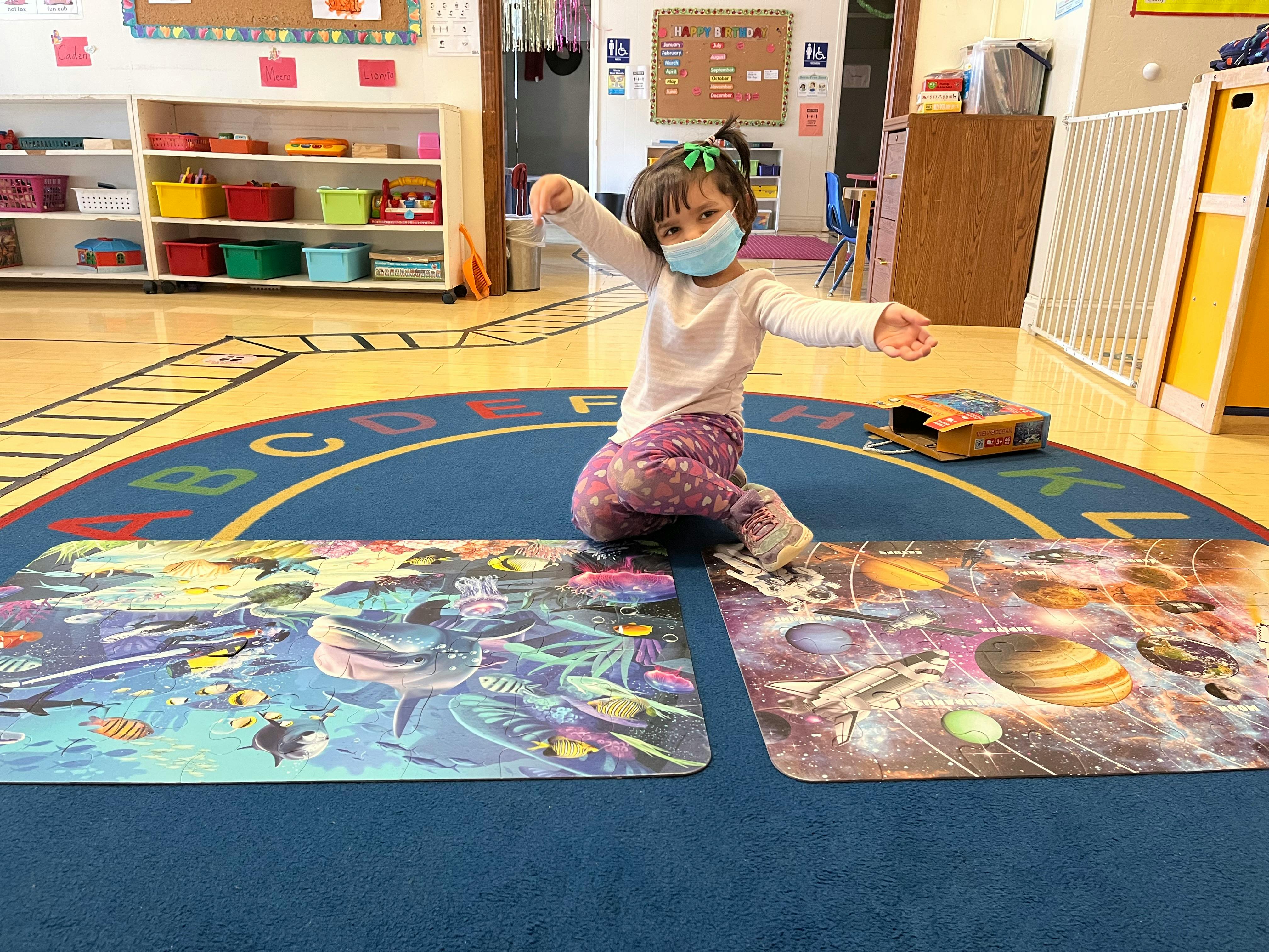 Child in a mask sitting on a rug with two large floor puzzles