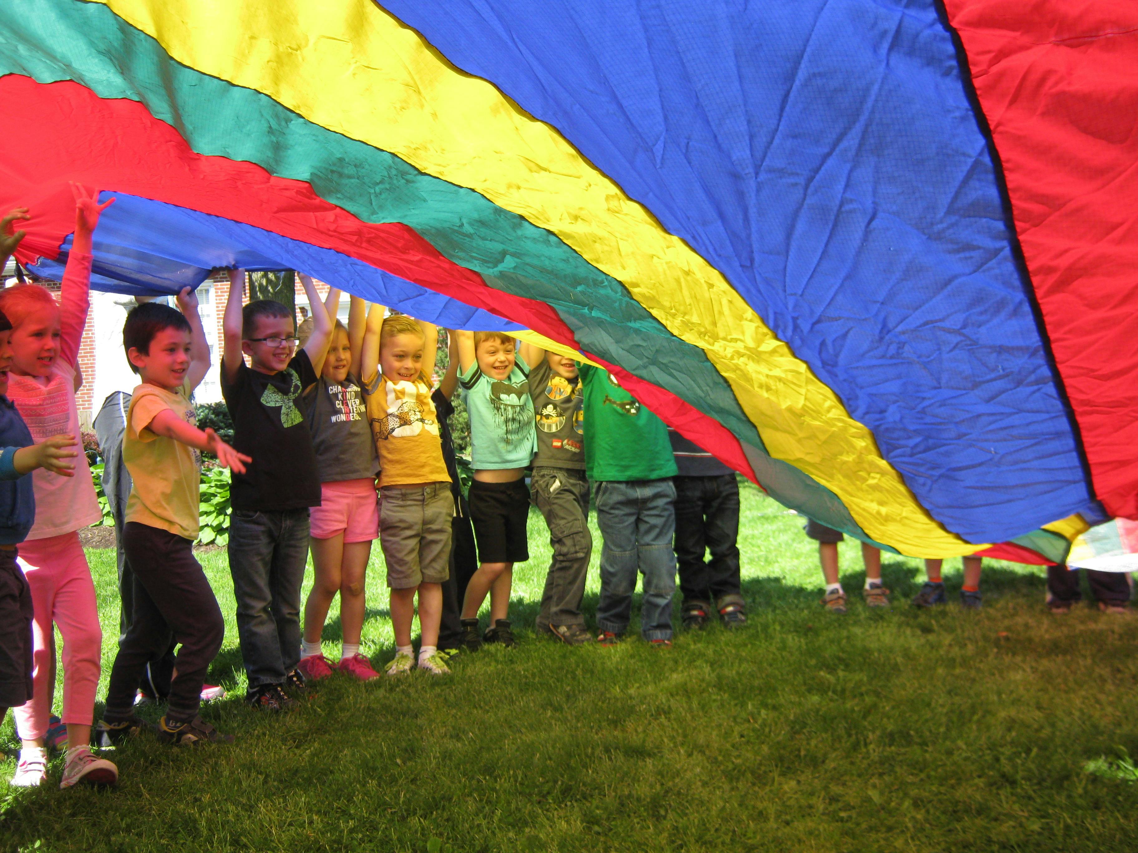 Children playing with a colorful parachute outdoors