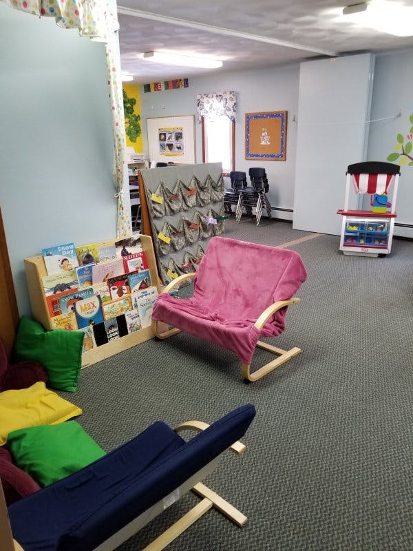 Children's reading area with book display, chairs, and play stand