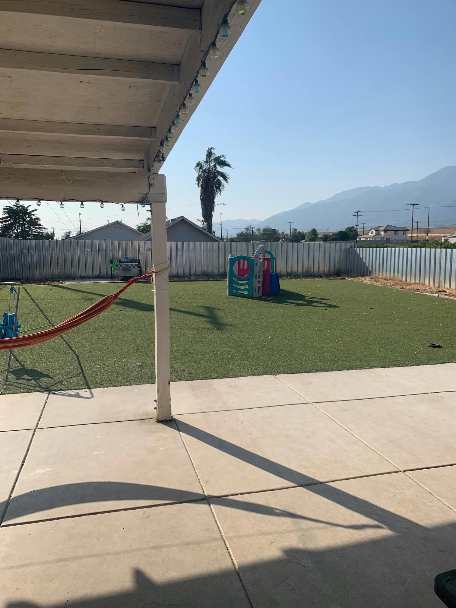 Patio overlooking a backyard with artificial turf and a small play structure
