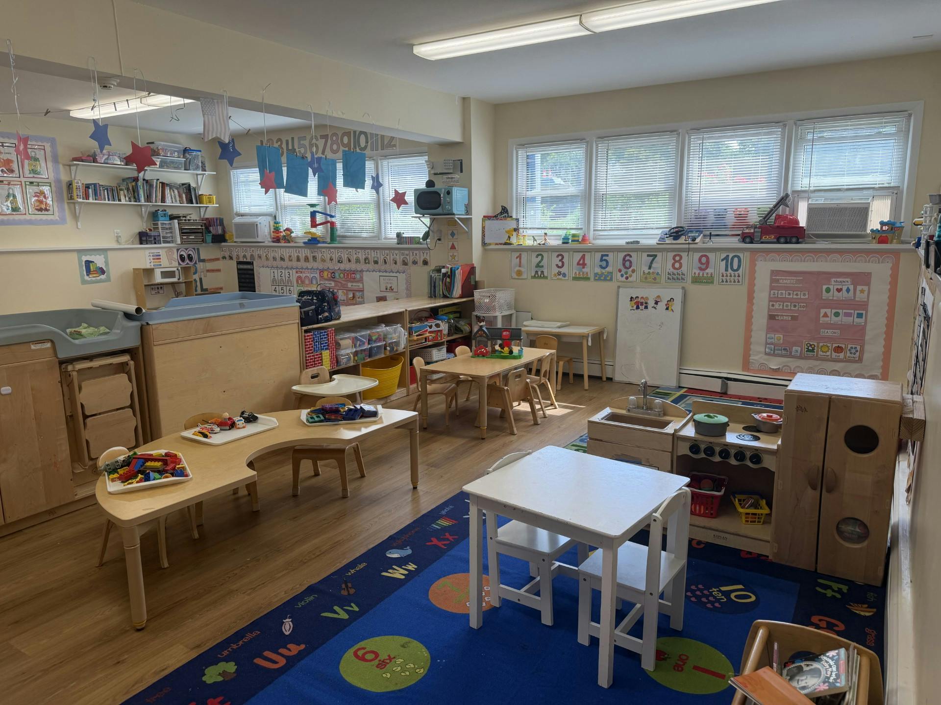 Empty preschool classroom with small tables and educational decorations