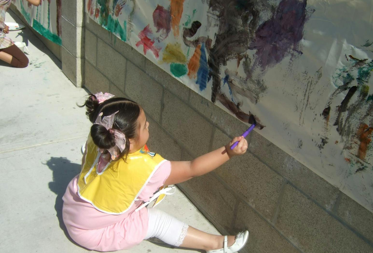 Child painting on a wall with a brush