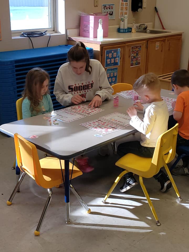 Person and three children sitting at a table with papers