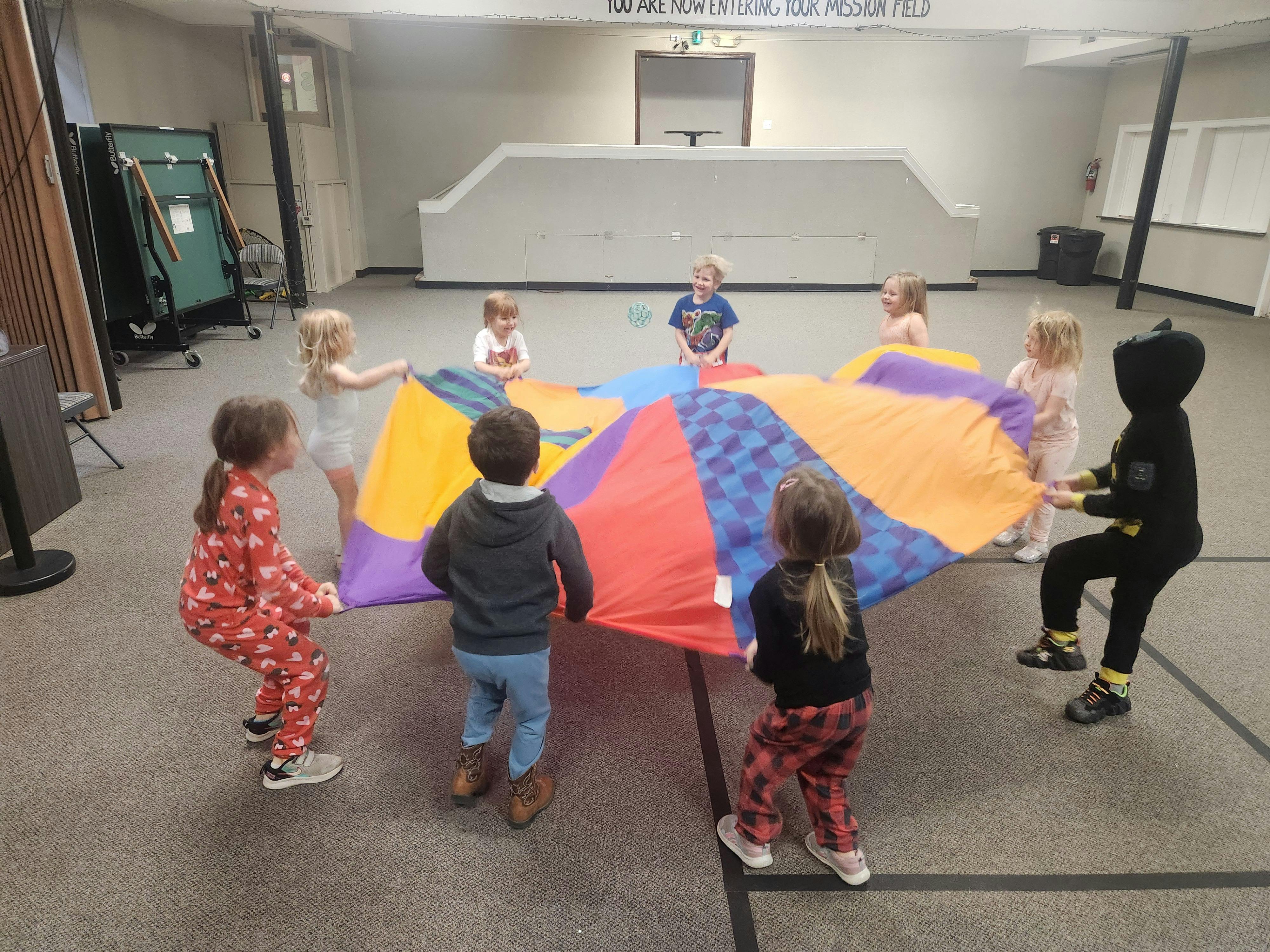 Children playing with a colorful parachute