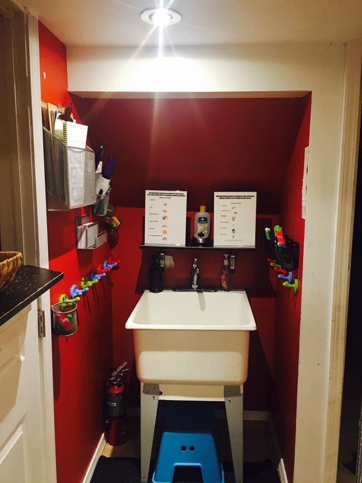 Utility sink with red walls and a blue step stool