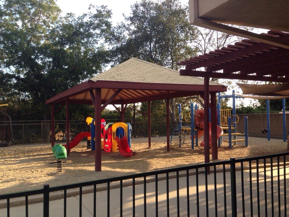 Playground with sand, colorful play structures, and a covered area