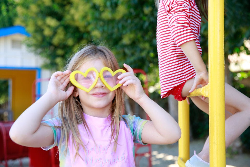 Child holding heart-shaped glasses over eyes