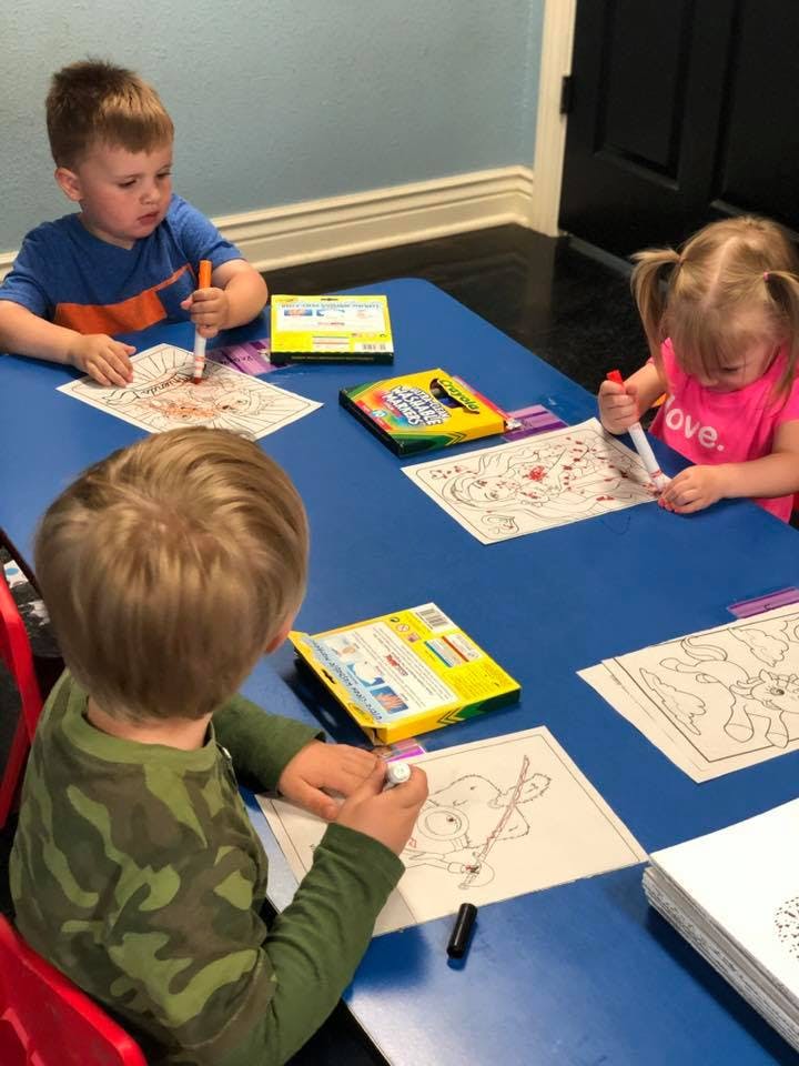 Three children coloring at a blue table