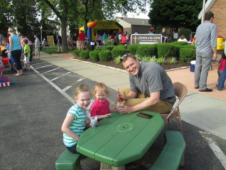 Person and two children at a green picnic table
