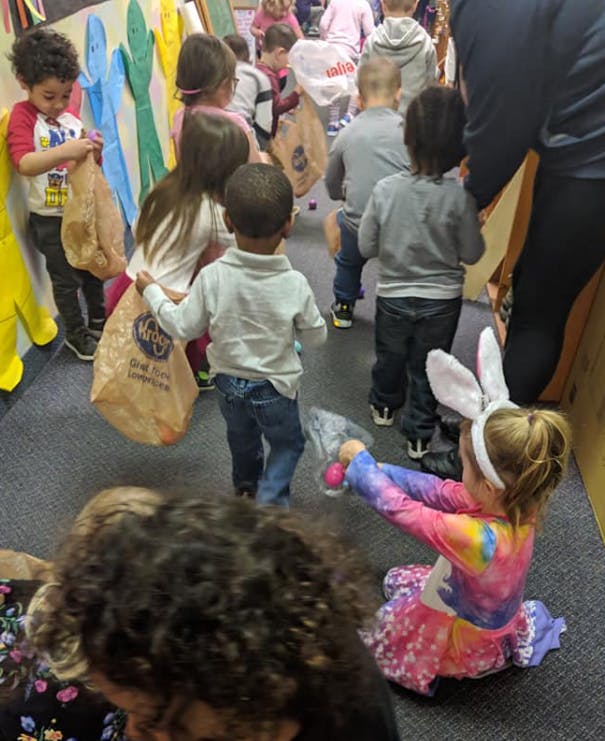 Children in a line holding bags, one child in bunny ears sitting on floor