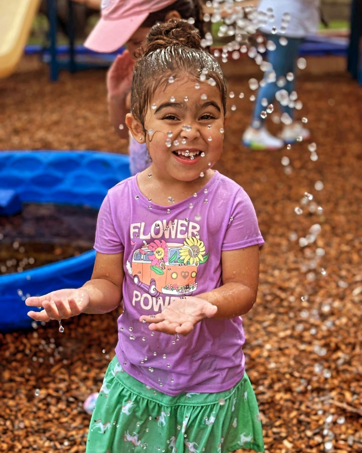 Child with water drops on face and hands