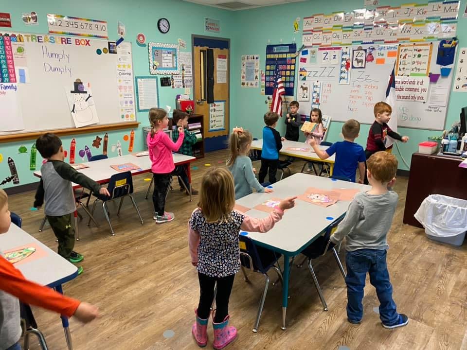Children standing and interacting in a classroom